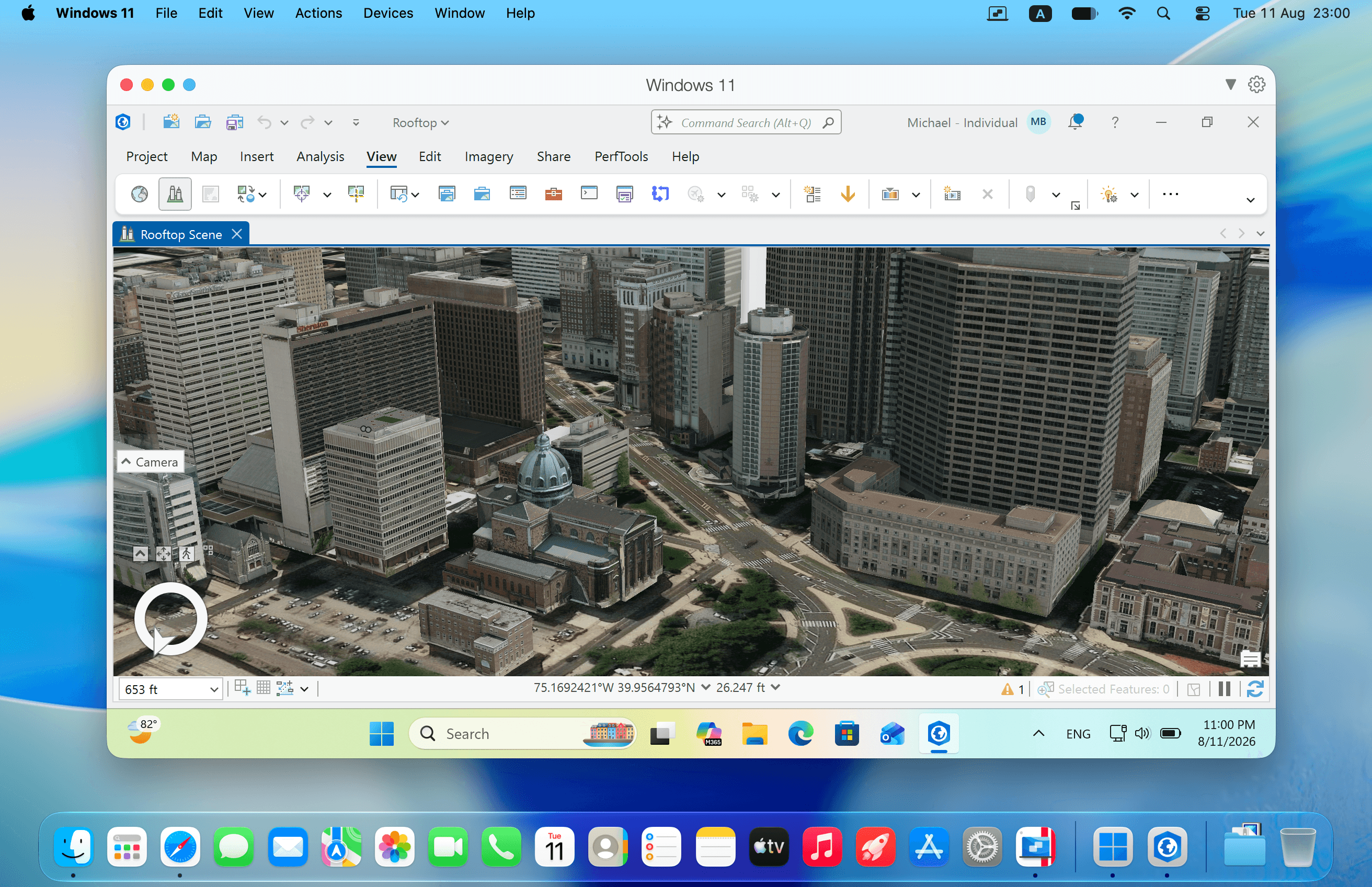 A Mac screen with one Parallels Desktop window titled Windows 11: inside it a Windows mapping application shows a 3D aerial view of a city's office towers and a domed building under a tab labeled Rooftop Scene, with the Windows 11 taskbar along the bottom of the window, the macOS menu bar across the top of the screen and the macOS Dock below.